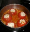 Выложить дно сотейника луком и чесноком и поставить фаршированные начинкой помидоры