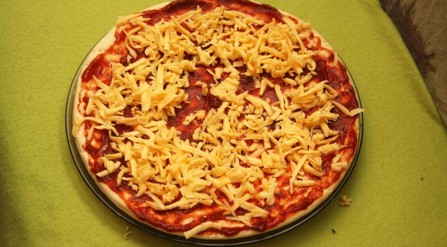 Посыпать тертым сыром основу для пиццы