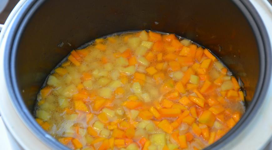 Добавить к луку картошку, тыкву, специи и кипяток, тушить овощи домягкости