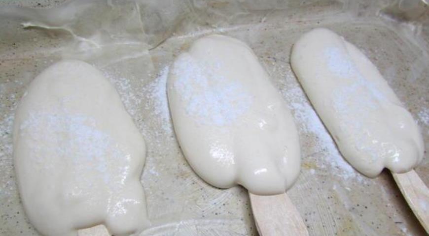 На пекарскую бумагу кладем палочки от мороженого и выкладываем на них тесто