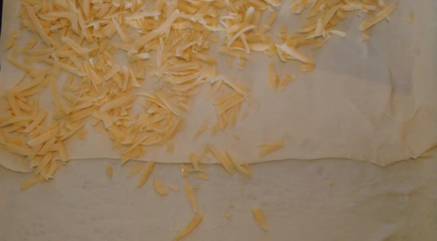 Выкладываем тесто на противень и сверху посыпаем сыром