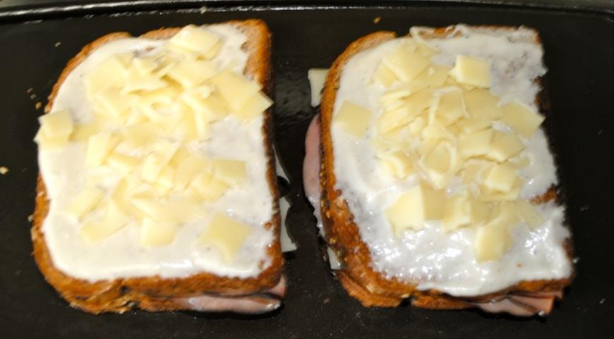 Сверху на тосты распределяем соус бешамель и сыр, затем ставим в духовку запекаться