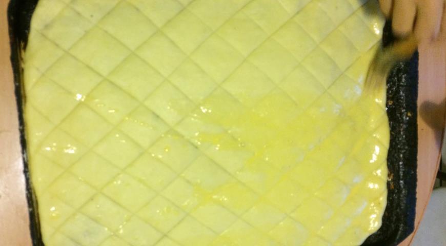 Промазываем тесто желтком для приготовления сладости
