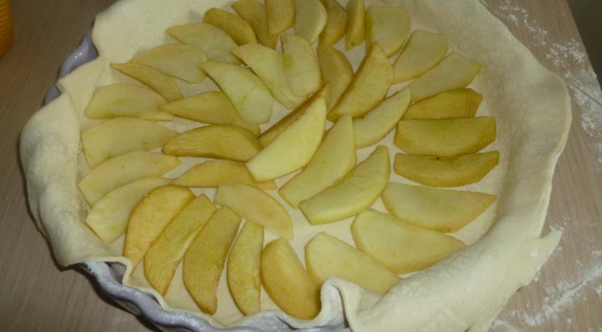 Смазать форму маслом, выложить тесто и яблоки