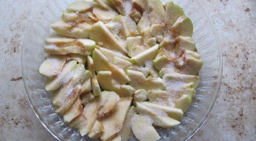 Выложить дно формы яблоками, добавить сахар и корицу