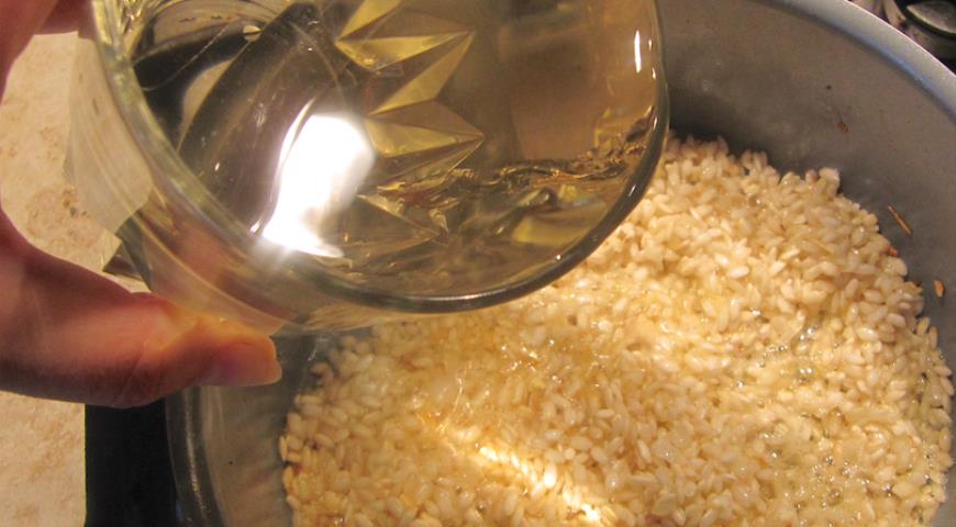 Добавить в рис вино, выпарить, затем постепенно добавлять бульон