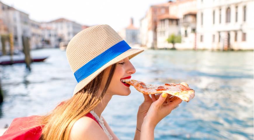 Туристка ест пиццу в Италии