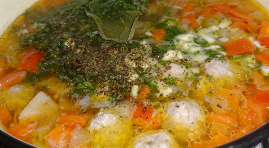 Добавляем в овощной суп с фрикадельками нарезанные перец, укроп и чеснок. Посолить, поперчить, добавить лавровый лист