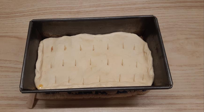 Раскатать тесто и выложить поверх яблок для приготовления пирога