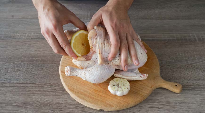 Курица, запеченная в фольге, положите головку чеснока и половину лимона в полость курицы