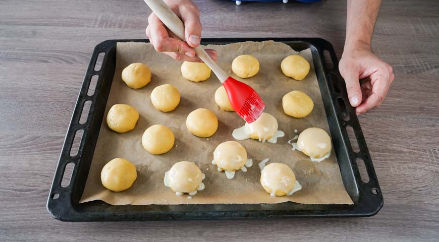 Печенье с ананасовым джемом внутри, выложите готовые шарики на противень, смажьте сгущеным молоком
