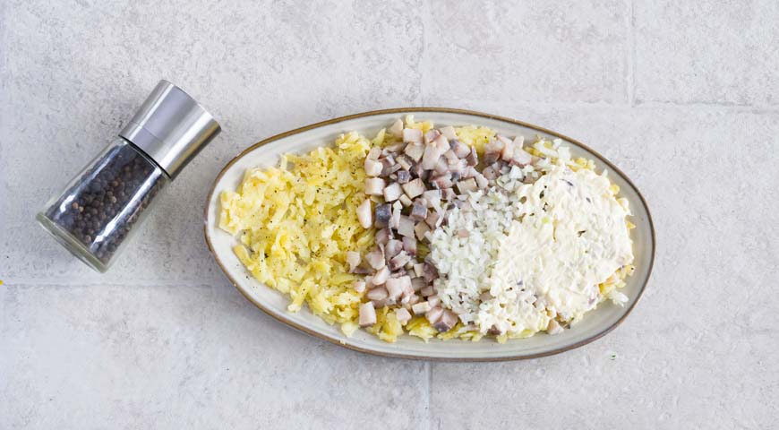 Селедка под шубой, выложите на тарелку половину картофеля и поперчите, затем — слой сельди и лука 
